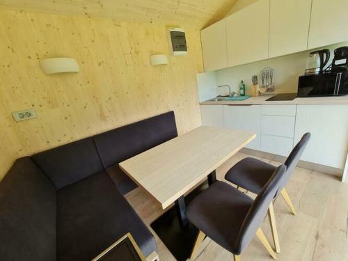 uma cozinha com uma mesa de madeira e 2 cadeiras pretas em Ferienhaus Woodcube Großkirchheim em Grosskirchheim