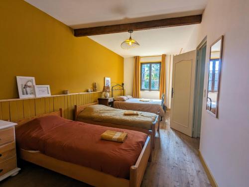 - 2 lits dans une chambre aux murs jaunes dans l'établissement Sweet Home Dordogne between Sarlat-Souillac, à Peyrillac-et-Millac