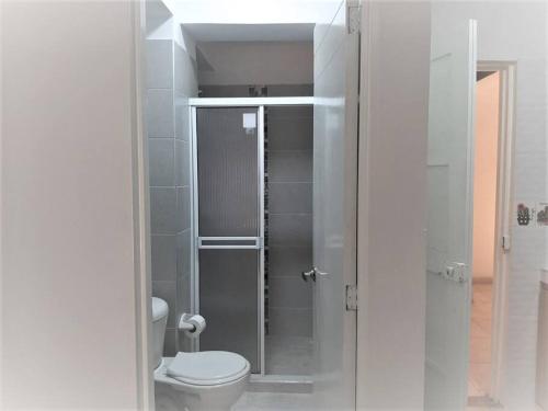 uma casa de banho com um WC e uma cabina de duche em vidro. em Apartaestudios White And Grey em Popayán