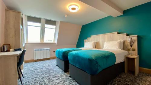 1 dormitorio con 1 cama grande y pared azul en The Bath Rooms en Morecambe