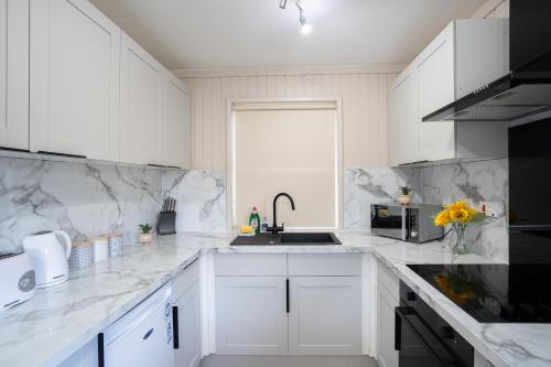 una cucina bianca con armadi bianchi e lavandino di Lodge -3 Bedrooms - Hunters Quay a Kilmun