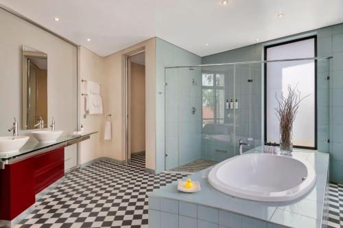 a bathroom with a tub and two sinks and a shower at African Pride Melrose Arch, Autograph Collection in Johannesburg