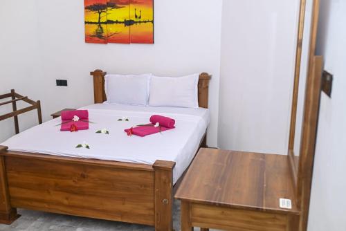a bedroom with a bed with pink chairs on it at Negombo Royal Villa by Hotel Oviniru in Negombo