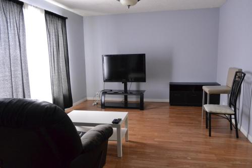 sala de estar con sofá y TV de pantalla plana en Private Bedroom on the main floor with shared washroom - Erin Woods en Calgary