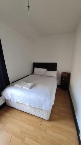 Schlafzimmer mit einem weißen Bett und Holzboden in der Unterkunft Little house in the City in Dublin