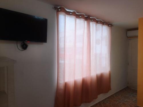 a curtain in a room with a television on a wall at Hotel Carmita in Atacames