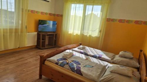 a bedroom with a bed and a flat screen tv at Agapé Vendégház in Cserépfalu