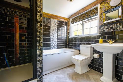 a bathroom with a sink and a toilet and a tub at Luxury 3 Bed Manor House HotTub Cinema in Saffron Walden