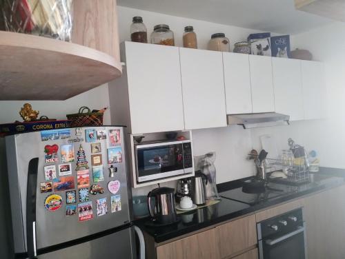 a kitchen with a refrigerator with magnets and a microwave at Linda habitación baño privado en casa de familia desayuno incluido in Lima