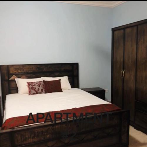 a bedroom with a large bed and a wooden cabinet at Brusubee, phase 2 in Banjul