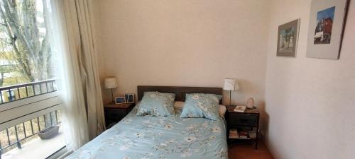 Chez Catherine في Fontenay-le-Fleury: غرفة نوم بسرير وملاءات زرقاء ونافذة