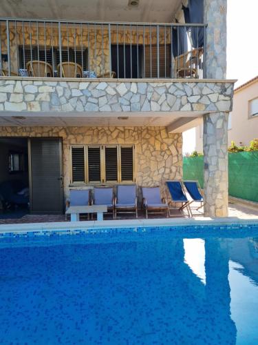 une piscine avec des chaises et une maison en arrière-plan dans l'établissement Villa Isabelita, piscina privada y salida a playa, à Tavernes de Valldigna