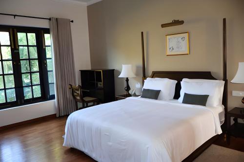 a bedroom with a large white bed with two pillows at Chimneys Nuwara Eliya in Nuwara Eliya