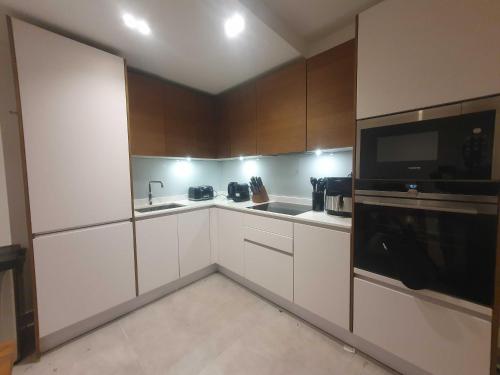 a small kitchen with white cabinets and a microwave at Bright 2Bed - 2Bath Flat - Kentish Town in London