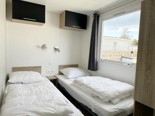 two beds in a room with a window at Chalet 1a op Recreatiepark De Wielen in Sint Maarten