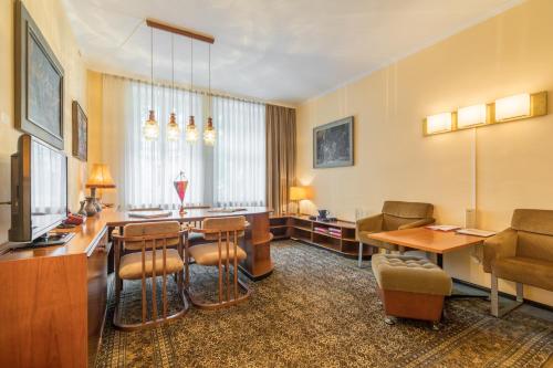 ein Hotelzimmer mit einem Wartebereich mit einem Tisch und Stühlen in der Unterkunft Galerie Hotel Leipziger Hof in Leipzig