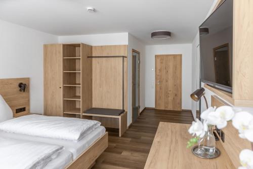 Schlafzimmer mit einem Bett und einem Schreibtisch mit einem TV in der Unterkunft Gasthof Zum Roten Haus 
