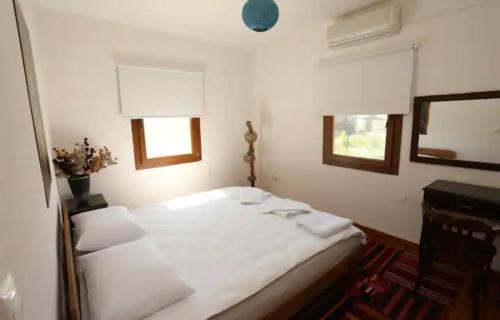 a bedroom with a white bed and a mirror at Pelazzi Çiftliği - Farm House in Bozcaada