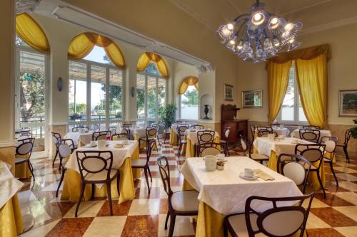 un restaurante con mesas y sillas y una lámpara de araña en Ena Hotel, en Arenzano