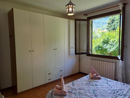 une chambre avec un lit et une grande fenêtre dans l'établissement Villetta singola con giardino Cottage Ghisallo zona Bellagio, à Magreglio