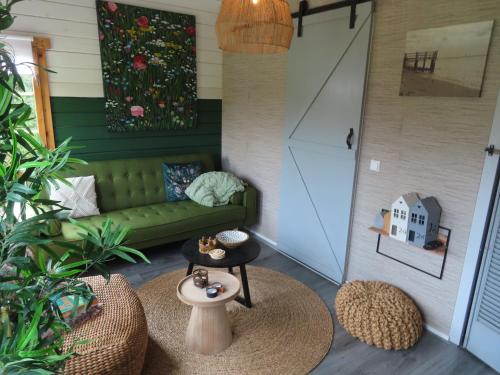 ein Wohnzimmer mit einem grünen Sofa und einem Tisch in der Unterkunft Tiny Botanic House in Tzummarum