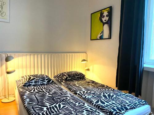 Small home in Kamppi في هلسنكي: غرفة نوم مع سرير بملاءات مطبوعة لحمار الوحشي