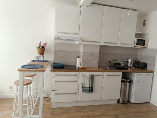 une cuisine avec des armoires blanches et un comptoir dans l'établissement Appartement aux Portes de Paris, métro 12, à Aubervilliers