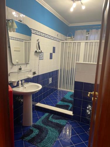 un bagno blu e bianco con lavandino e doccia di CasAle a Borgetto