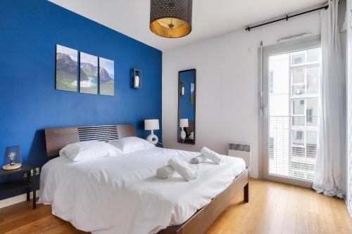 um quarto com uma grande cama branca e uma parede azul em Sejour sur l ile de Nantes avec vue sur la Loire em Nantes