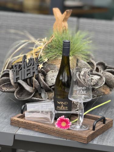 a bottle of wine and a glass on a wooden tray at Gästehaus Wind und Meer in Norddeich