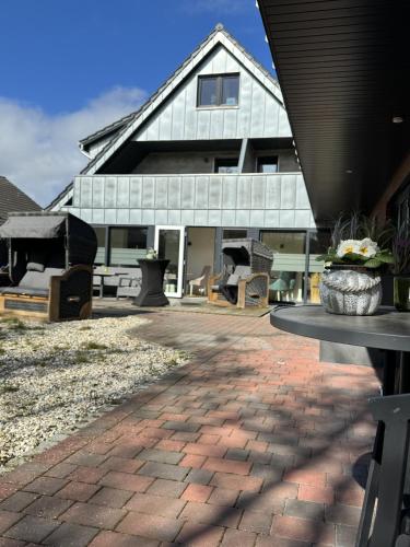 a house with a brick patio with a table at Gästehaus Wind und Meer in Norddeich