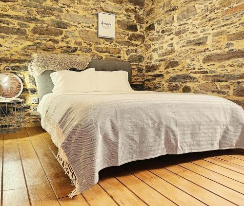 ein Schlafzimmer mit einem Bett mit einer Steinmauer in der Unterkunft PampiHouse in Pampilhosa da Serra