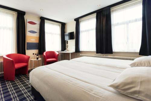 um quarto com uma cama grande e 2 cadeiras vermelhas em Hotel Van der Maas em Ootmarsum