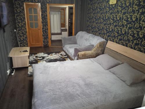ein Schlafzimmer mit einem Bett, einem Sofa und einem Stuhl in der Unterkunft Апартаменты посуточно по Ауэзова in Öskemen
