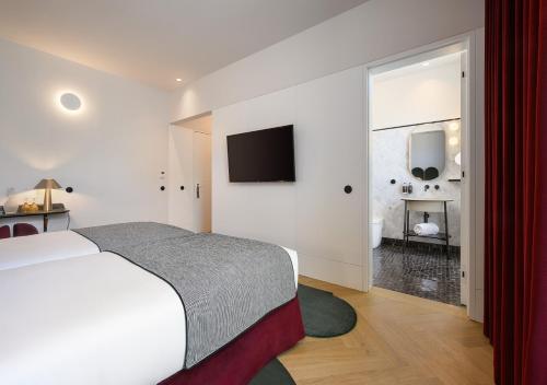 a bedroom with a bed and a television on the wall at Montebelo Vista Alegre Lisboa Chiado Hotel in Lisbon