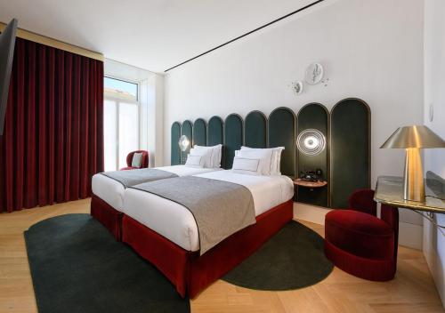 a bedroom with a large bed and a red chair at Montebelo Vista Alegre Lisboa Chiado Hotel in Lisbon