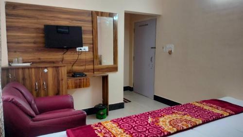 a bedroom with a bed and a chair and a television at Milan Palace Deoghar in Deoghar