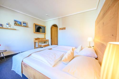 a bedroom with a large bed with white sheets at Biohotel Garmischer Hof in Garmisch-Partenkirchen