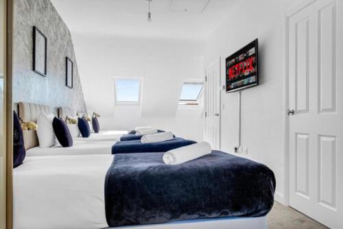 a room with a row of white beds with blue pillows at 3Bed House For Contractors Large Group Sleep upto9 in Birmingham