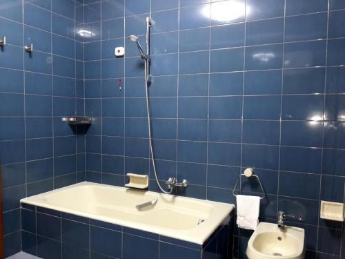 La salle de bains est pourvue de carrelage bleu, d'un lavabo et de toilettes. dans l'établissement Camera Panoramica in Villa vista Mare e Vesuvio, à Massa Lubrense