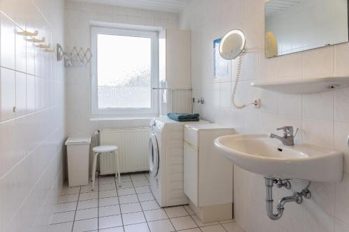 ein weißes Badezimmer mit einem Waschbecken und einer Waschmaschine in der Unterkunft 50187... in Harlesiel