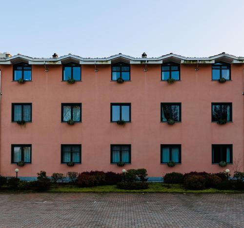 a red building with black windows and plants at Hotel Villa Delle Rose - Malpensa in Oleggio