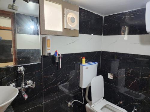 a black tiled bathroom with a toilet and a sink at 2BHK fully furnished apartment in Indore