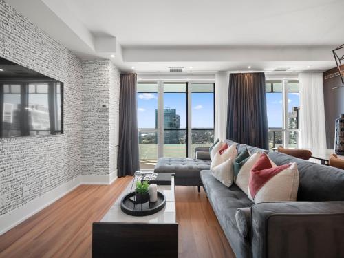 a living room with a gray couch and windows at Stylish One Bedroom Suite - Entertainment District Toronto in Toronto