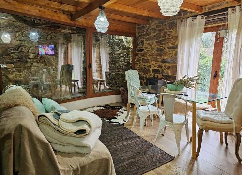 sala de estar con mesa y pared de piedra en PampiHouse, en Pampilhosa da Serra