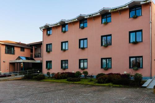 a large orange building with black windows and plants at Hotel Villa Delle Rose - Malpensa in Oleggio