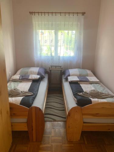 two twin beds in a room with a window at Ádám és Anett Vendégház in Mezőkövesd