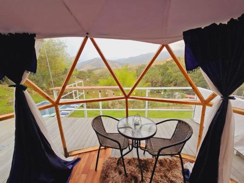 a glass table and two chairs in a tent at Glamping y Cabañas Alpina in Buga