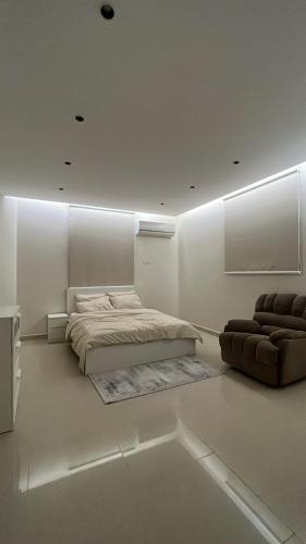 a white bedroom with a bed and a chair at شقه فاخره in Unayzah