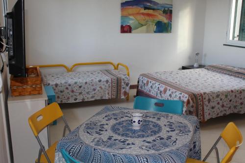 a room with two beds and a table and chairs at Gioiosa Marea Appartamento per 4 con vista sulle Eolie Casa Spisidda "Panarea" in Gioiosa Marea